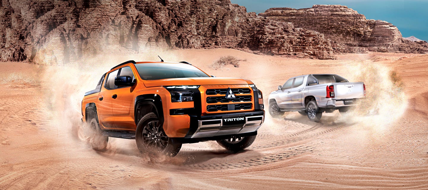 Orange Mitsubishi Triton pickup driving through desert terrain